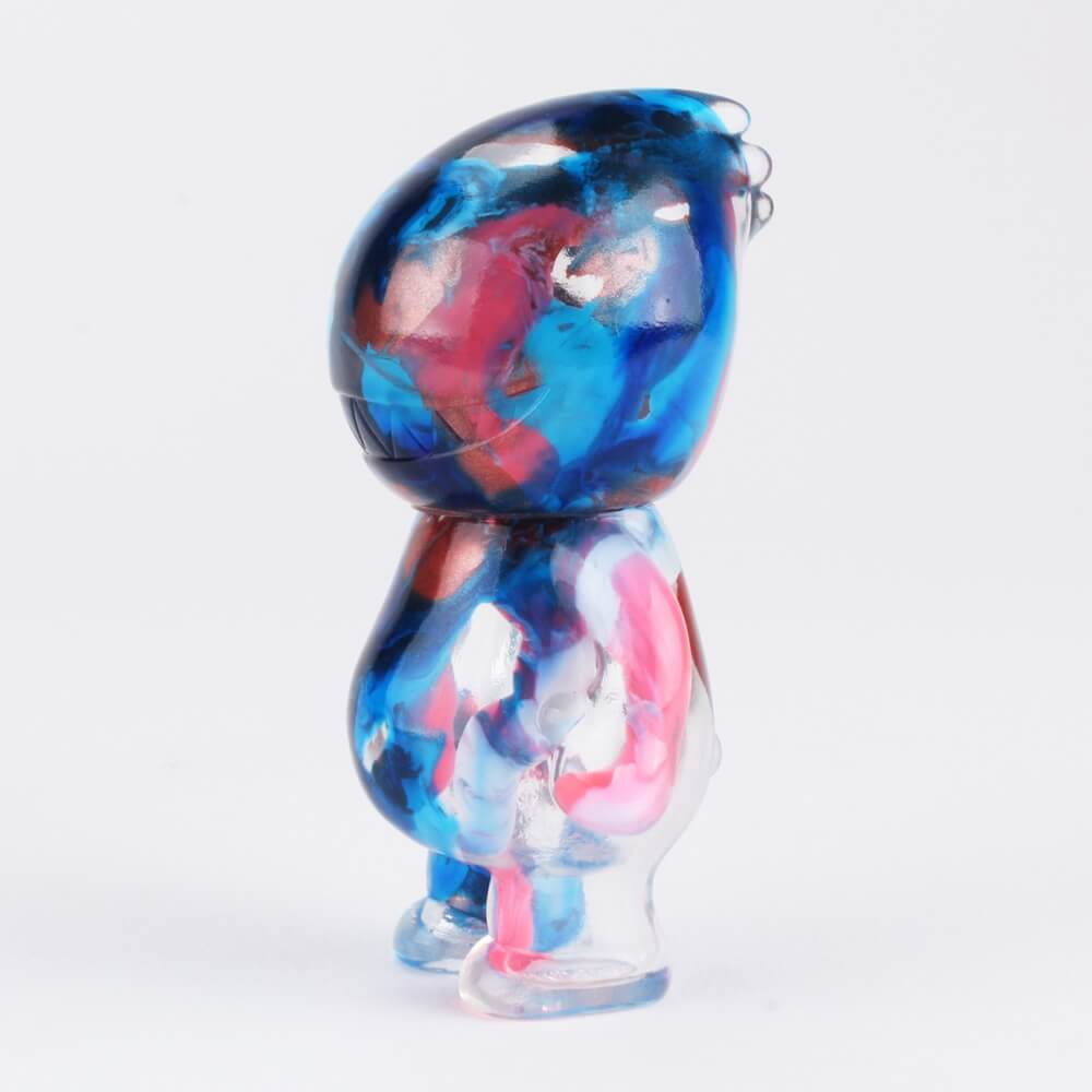 Cast in clear vinyl and painted with a red and blue marbled paint scheme, the Sogno Marbled Bastard stands 2.75 inches tall. As much as Uamou is a pure hearted alien boy, Bastard is a foul-mouthed, bratty little kid who talks behind everybody’s back and is just incredibly unpleasant to have on your picnic. We don’t think he is bad though, probably he is just asking for attention. Bastard will be available at SDCC Booth 5248, Squibbles Ink + Rotofugi, for $44 (tax included) and is a limited edition of 25 pieces. Any stock that remains after the convention will be made available on rotofugi.com approximately one week later.